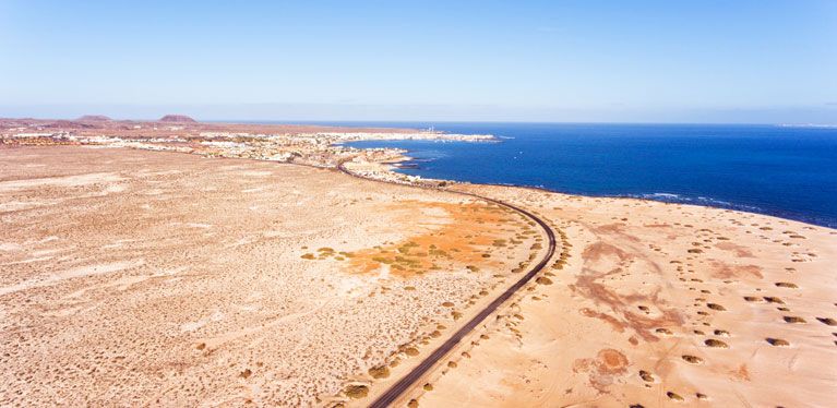 Straße schlängelt sich durch den Sand entlang der Küste von Fuerteventura