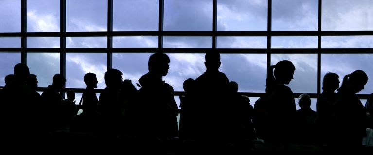 Passagerare i en lång kö på flygplatsen