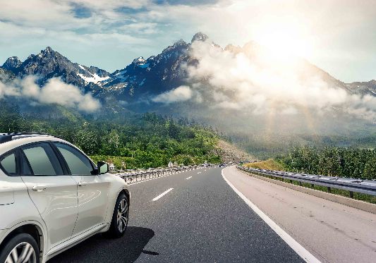 A car drives down a motorway in a mountainous environment