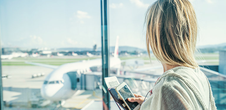 Une femme regarde au loin à travers la fenêtre du terminal des départs