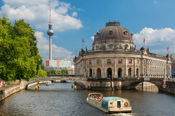 Historic Bode Museum and Museum Island in Berlin - domed building with river in front with two arched bridges and boats