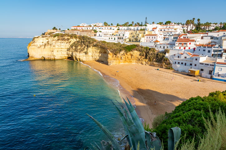 Golden beaches, cliffs, blue sea and sky above the village houses of Carvoeiro Algarve