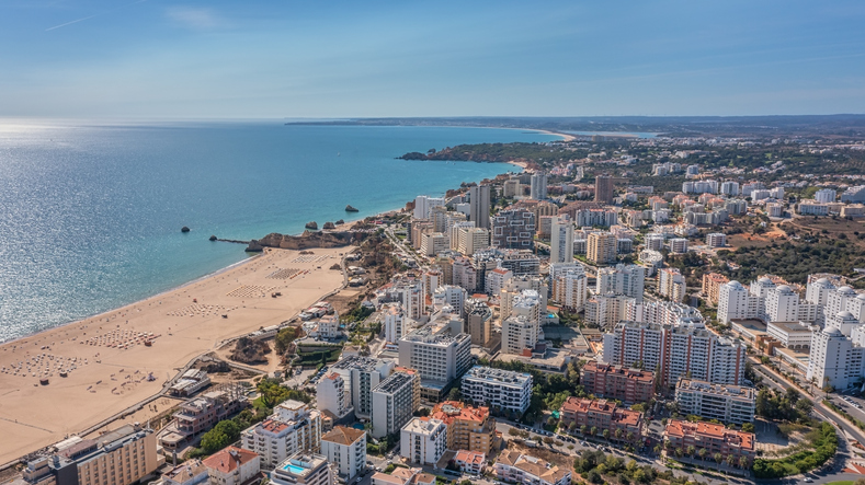 Aerial view of the city of Portimao over residential buildings, high-rise buildings, on the beach Praia de Rocha with tourists