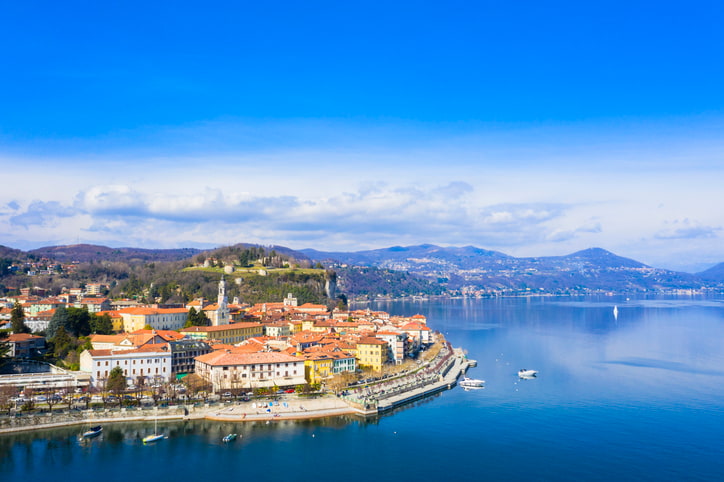 The blue waters of Lake Maggiore with the town of Arona behind buildings with terracotta roofs