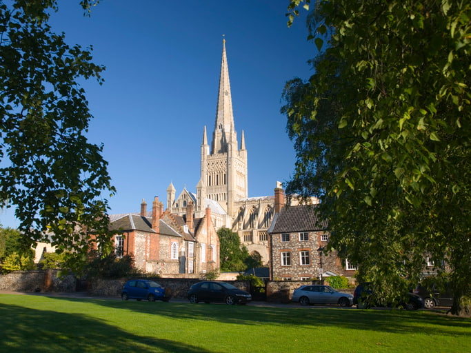 The spire of Norwich cathedral and blue sky behind the city's Cathedral Close