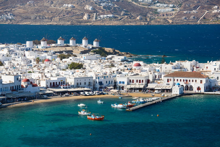 Mykonos town with blue sea and white-painted houses and the famous windmills on the skyline