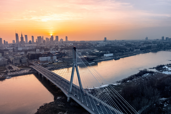 Bridge over River Vistula in Warsaw at sunset showing river, bridge and cityscape in orange glow