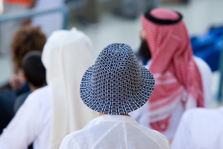 Persone in abito tradizionale multietnico sulle tribune del circuito di gara di Lusail, Doha.