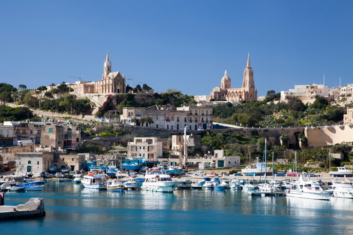 Gozo Malta coast with white cliff top buildings blue sea and sky