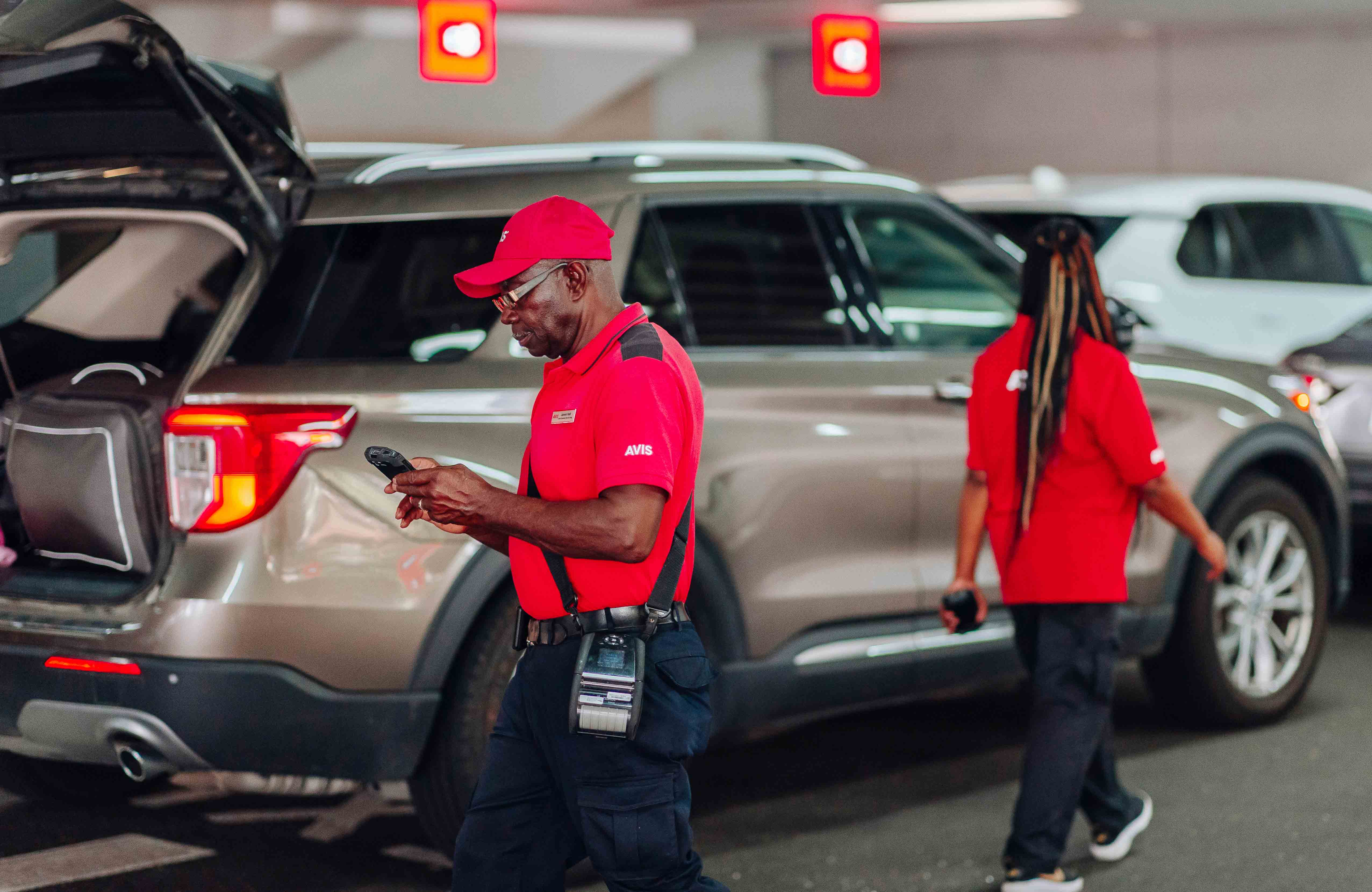 Avis-medewerkers aan het werk op een parkeerterrein van een verhuurlocatie