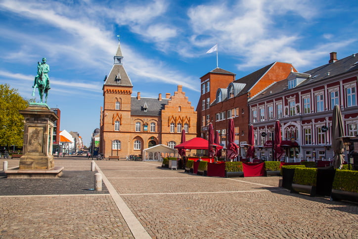 Red brick buildings in Scandinavian style, cobbled streets and horse statue in main square of Esbjerg Denmark