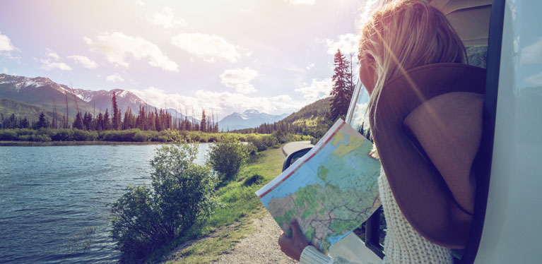 A woman leans out of her hire car window with a map