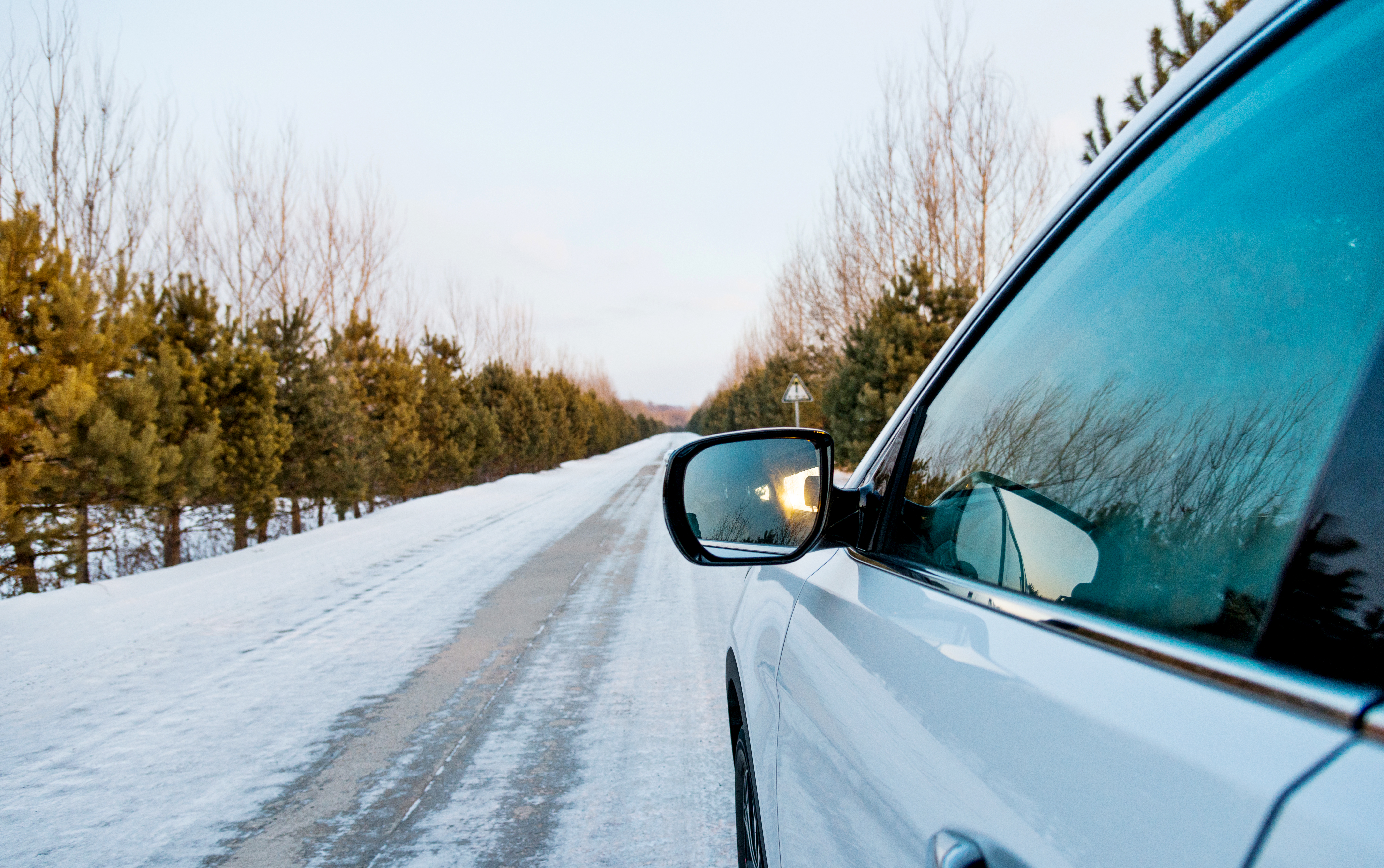 Image montrant une femme détendue sur le capot de sa voiture de location